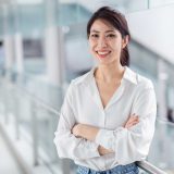 smiling-asian-businesswoman-blur-office-building-background